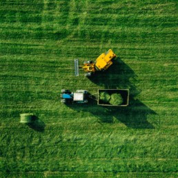 Aerial view of harvest field with tractor moving hay bale